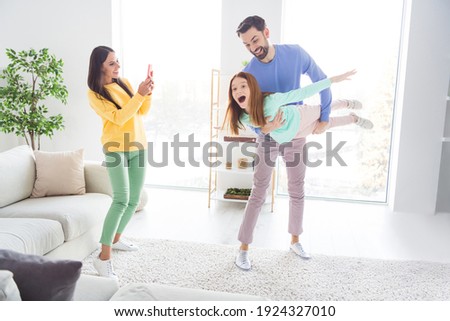 Photo portrait of mom taking photo of daughter playing with father flying like plane happy overjoyed at home