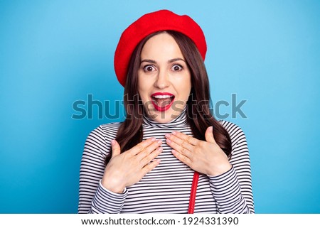Photo portrait of pretty girl smiling amazed hands on chest wearing beret striped turtleneck isolated bright blue color background