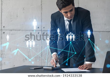 Businessman in office signs contract and social media hologram. Double exposure. Formal wear. Concept of people smm data.