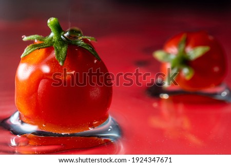 small red cherry tomatoes, in water with falling drops, frozen motion, close-up