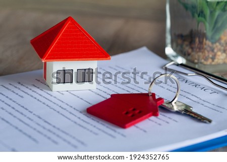Orange house And a bunch of red house keys on the contract Contract concept, signature in document, partner, customer, customer who buys products or contracts for home.