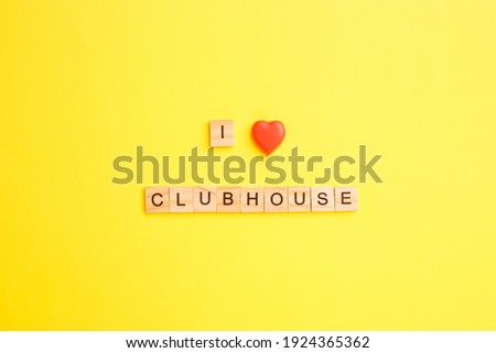 Wooden blocks with letters form the words I love clubhouse on a yellow background.