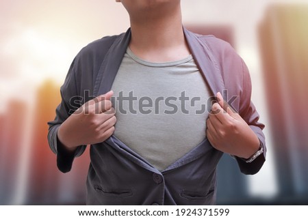 Junior businessman tearing off his suit, showing his underwear t-shirt over the city as background Successful entrepreneur concept