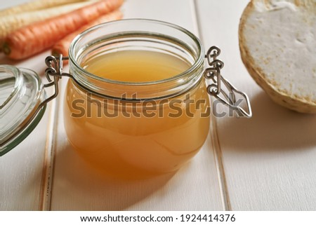 Bone broth in a glass jar on white wooden background