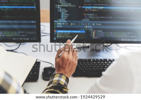 programmer writing program code with two monitors and working on new software or hacker programming developing software applications in the office. Royalty-Free Stock Photo #1924429529