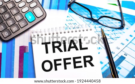 The desktop contains colored tables, a calculator, glasses, a pen and a notebook with the text TRIAL OFFER.
