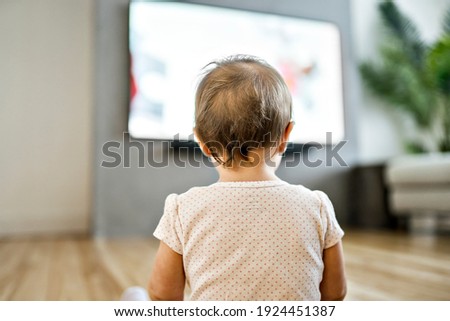 A baby watching tv view from back head