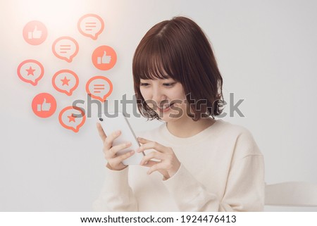 a woman looking at the screen of a smartphone and icons that imaged SNS