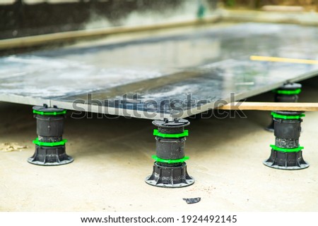 Slope-adjustable pedestal used for paver, bearer support instead of bedding sand brick, concrete, metal piers. Raised pavers deck construction. Royalty-Free Stock Photo #1924492145