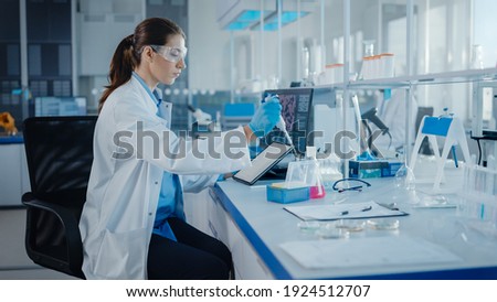 Modern Medical Research Laboratory: Female Scientist Working with Micro Pipette, Using Digital Tablet for Test Sample Analysis. Advanced Scientific Lab for Medicine, Biotechnology Development. Royalty-Free Stock Photo #1924512707