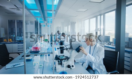 Modern Medical Research Laboratory: Team of Scientists Working with Pipette, Analysing Microbiological Sample, Talking. Advanced Scientific Lab for Drugs, Microbiology Development. High-Tech Equipment Royalty-Free Stock Photo #1924512737