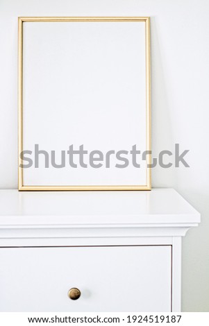 Golden frame for art, poster or photo in white interior, home decor concept
