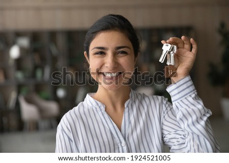 Headshot portrait of smiling young Indian woman hold show keys to new home or apartment. Profile picture of happy ethnic female renter or tenant celebrate moving relocation to own house. Rent concept. Royalty-Free Stock Photo #1924521005