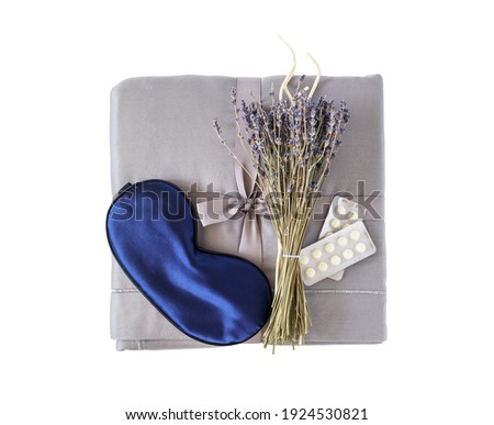 Isolated beautiful folded new grey set of bed linen with mask for sleep, bouquet of lavender and homeopathic pills. Insomnia or depression treatment. Top view