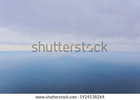 background, seascape - clouds and rains over the foggy winter sea, top view