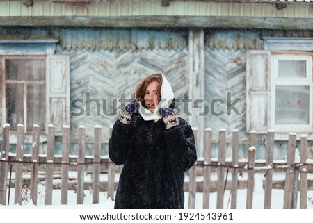 Portrait of a girl on the background of an old house. Winter.