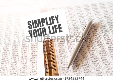 Text SIMPLIFY YOUR LIFE on paper card,pen, financial documentation on table - business, banking, finance and investment concept. close up of stock market chart.