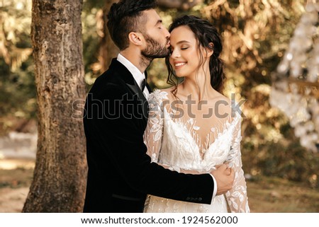 Beautiful wedding couple of newlyweds hugging on the background of the forest. Royalty-Free Stock Photo #1924562000