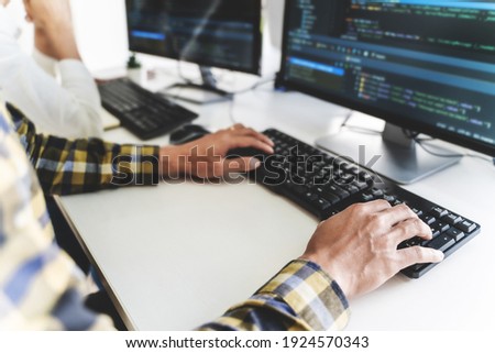 programmer writing program code with two monitors and working on new software or hacker programming developing software applications in the office.