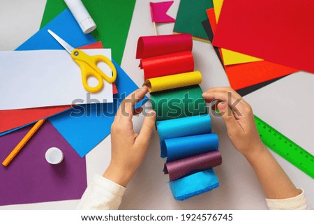 Girl Kid Makes a Sailboat out of Sponge and Colored Paper with a Rainbow flag. Family and School Education of Children Concept.