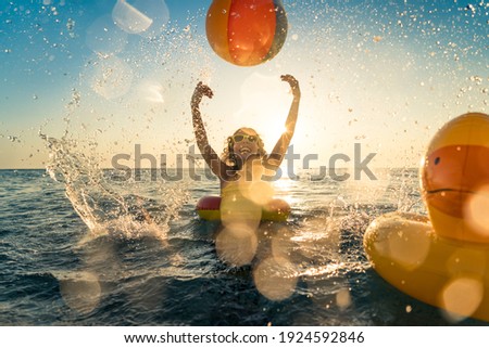 Happy child having fun on summer vacation. Kid playing with rubber duck and ball in the sea. Healthy lifestyle concept. Spring break! Royalty-Free Stock Photo #1924592846