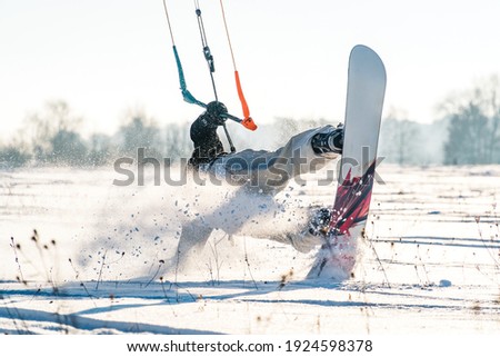 Backlit shot of Snowkiter doing a butterslide trick in fresh powder on a sunny day Royalty-Free Stock Photo #1924598378