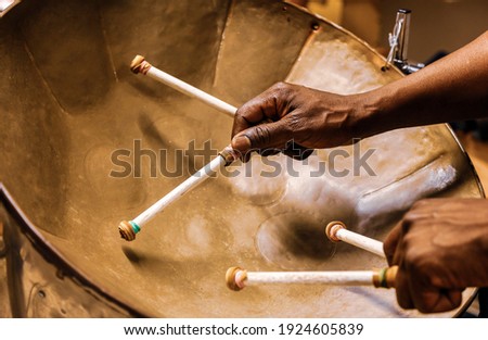 Afro american man plays the steel drum using two hands and four drumsticks Royalty-Free Stock Photo #1924605839