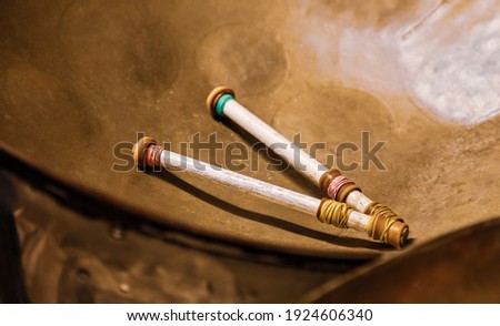 Two drumsticks resting in a steel drum Royalty-Free Stock Photo #1924606340
