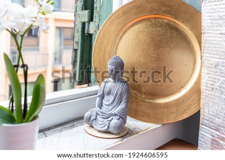 Buddha statue sitting on the table near window
 Royalty-Free Stock Photo #1924606595