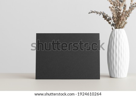 Black invitation card mockup with a dried lavender on a beige table. 5x7 ratio, similar to A6, A5.