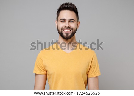 Young caucasian european smiling bearded happy attractive handsome student man 20s in casual yellow basic t-shirt look camera isolated on grey background studio portrait People lifestyle concept