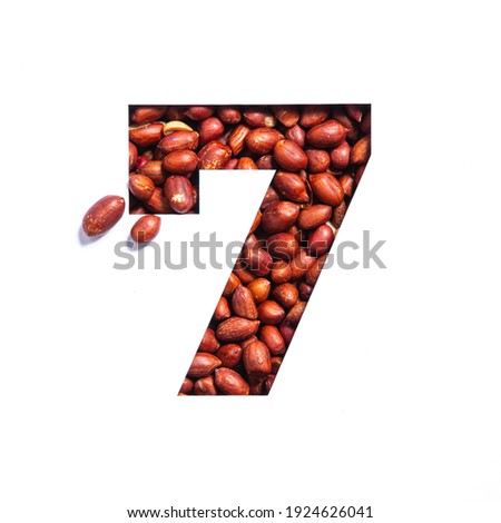Number seven made of peanuts and paper cut in shape of seventh numeral isolated on white. Font of groundnuts