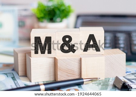 The letters M and S written on wood cubes. Pen, banknotes, calculator and green plant in a flower pot on the background. M and A - short for Mergers and Acquisitions, business concept. Royalty-Free Stock Photo #1924644065