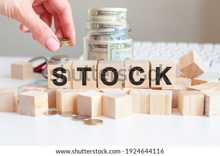 the word Stock on the wooden blocks and a bank with money in the background, business concept