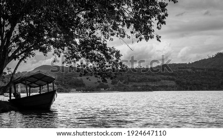 Boat, canoe, raft on the Huallaga River in the Peruvian high jungle. River among vegetation with light blue sky and white clouds. Black and white photography.