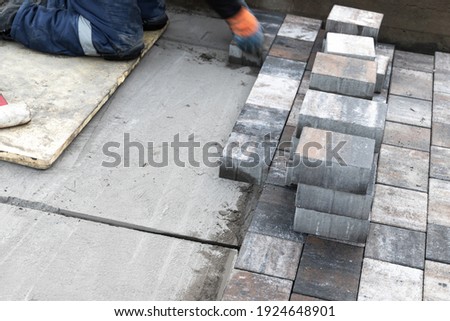 Worker with gray paving slabs, street paving is in progress. Background photo with selective focus