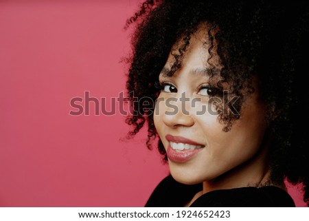 A freelancer smiles and poses in a photo studio. Portrait of a young woman of Afro appearance. Copy space. In a good mood.