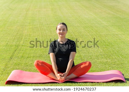 YOUNG PREGNANT WOMAN DOING YOGA OUTDOOR