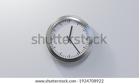 Glossy chrome clock on a white wall at twenty-four past twelve. Time is 00:24 or 12:24