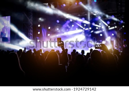 People with raised hands, silhouettes of concert crowd in front of bright stage lights Royalty-Free Stock Photo #1924729142