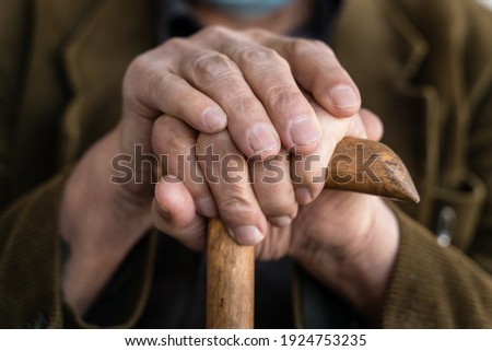 Close up on hands of unknown old caucasian man pensioner senior holding cane walking stick while sitting and waiting - real people old age senility concept copy space Royalty-Free Stock Photo #1924753235
