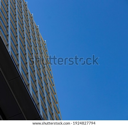 The side of an apartment building stands in stark contrast with the  impeccable blue sky behind it.