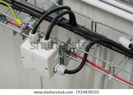 Insulated plastic box with glands and cables on a cable tray. Royalty-Free Stock Photo #1924838501