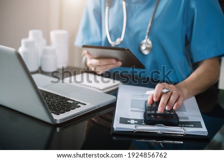 Doctor physician with tablet  calculate medical fee costs and revenue. practitioner use calculator at clinic.