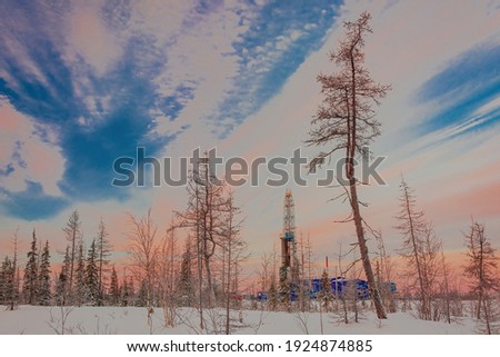 The landscape of the northern landscape of an oil and gas field with a drilling rig against the backdrop of a beautiful sky. Winter polar day