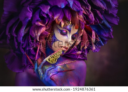 Beautiful young women with a lilac flower. Bright purple flower girl. Girl flower Fantasy girl with a flower on her head. Fantasy girl with very long nails