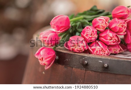 Bouquet of tulips on a wooden barrel. An armful of pink flowers lie on the table. Spring concept. Copy space. Composition for Women's Day March 8, Mother's Day.
