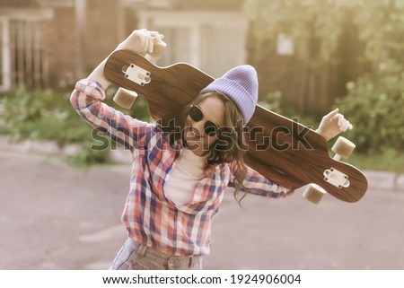 Lifestyle portrait happy girl with skateboard on sunset