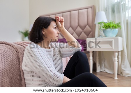 Unhappy tired depressed mature woman sitting at home on the floor. Health problems of middle-aged women, mental health, covid coronavirus consequences Royalty-Free Stock Photo #1924918604