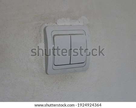 Dirty white light switch with dirty handprints on the dirty white wall background